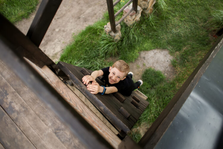 the boy climbs from bottom to top, passes an obstacle course, goes in for active sports, climbs a wooden obstacle
